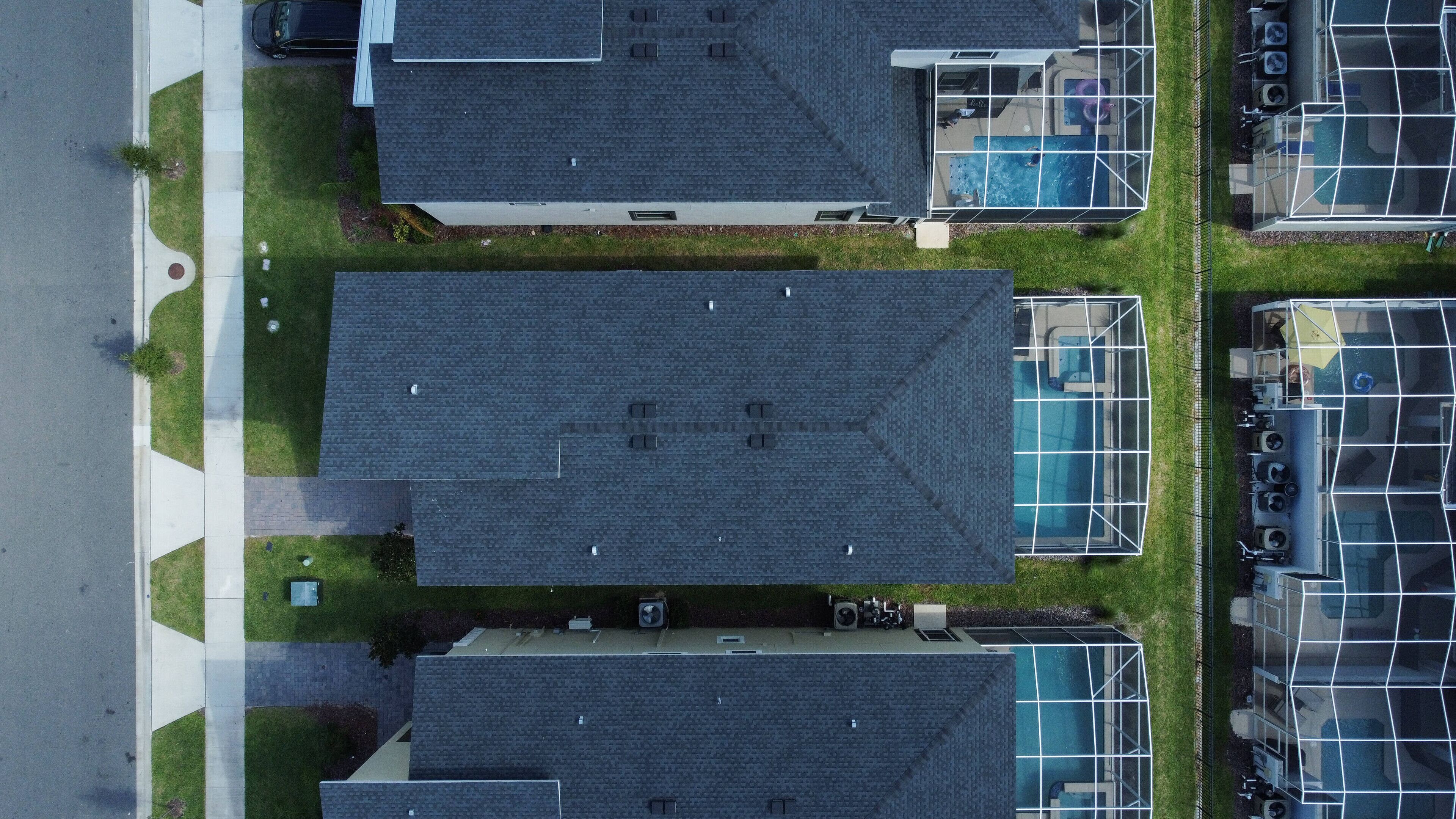 Vista aérea de una zona residencial con varias casas, cada una con techo inclinado y piscina.