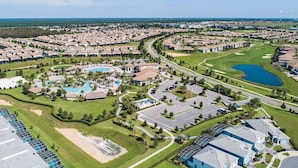 Vista aérea de una zona residencial con varios edificios, un campo de golf y una piscina.