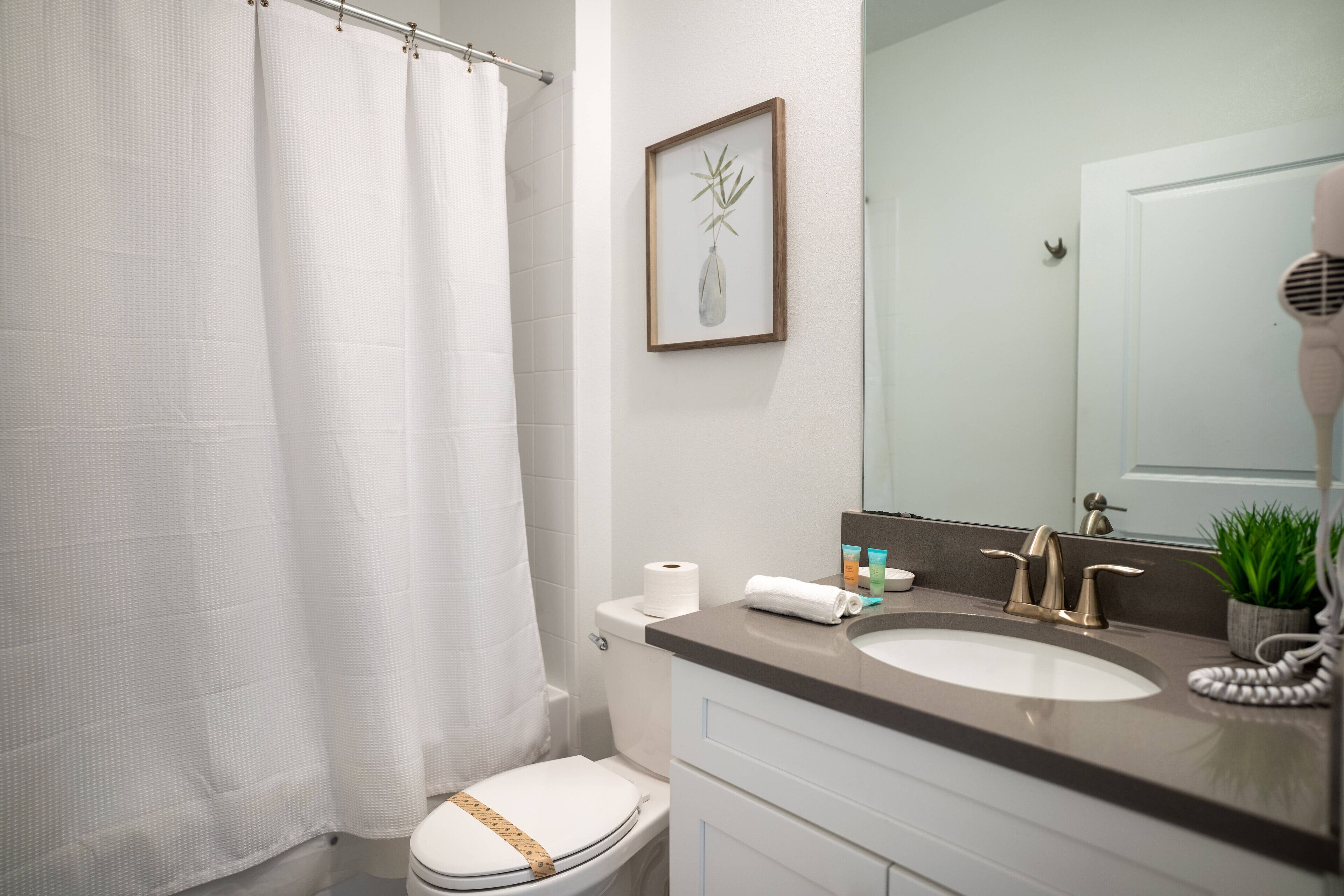 Un baño con inodoro, lavamanos y cortina de ducha.
