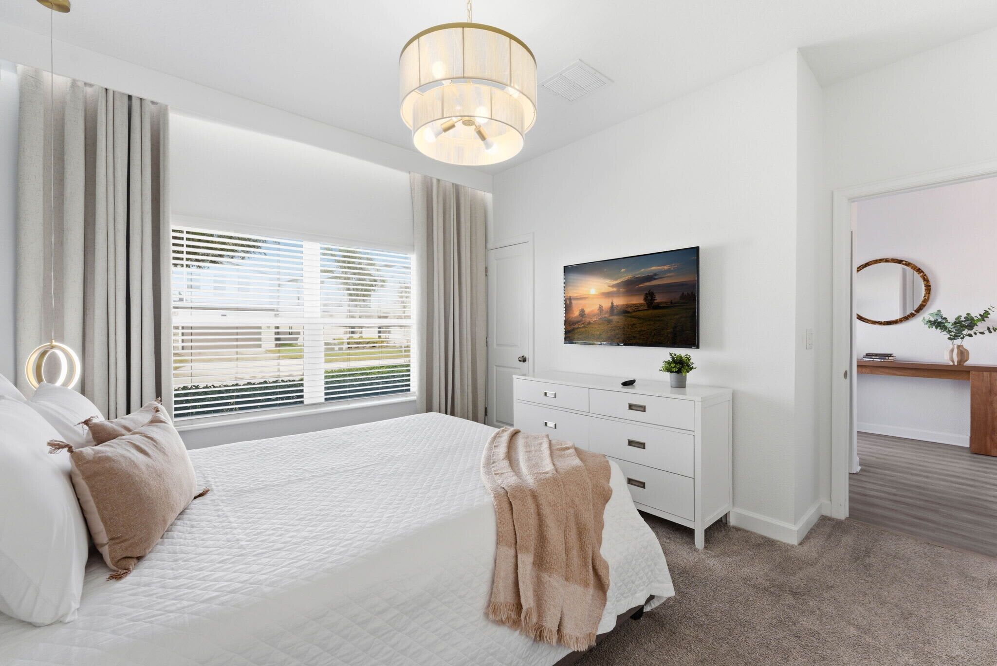 Une chambre à coucher avec un lit, une commode, un tableau et une fenêtre avec des stores.