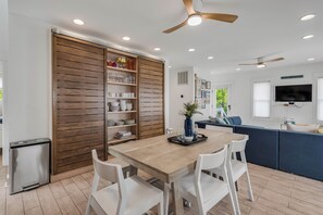 A modern kitchen with a wooden cabinet, white chairs, and a dining table. - Sunrise Bay Retreat • Private Beachfront (Scotland)