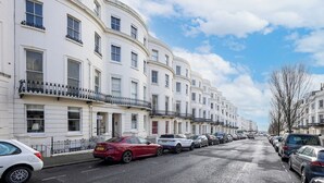 A row of white, multi-story residential buildings with balconies, parked cars, and a clear sky. - Stunning Period Character Courtyard Coastal Flat - Pass the Keys (Hove)
