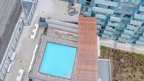 A high-rise building with a rooftop pool, adjacent to a modern residential building with balconies.