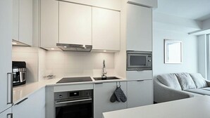 A modern kitchen with white cabinetry, a built-in microwave, and a stainless steel range hood.