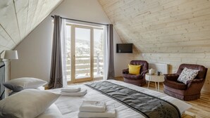 Une pièce confortable avec un lit, deux fauteuils, une petite table et un téléviseur.