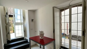 Ein Zimmer mit einem roten Tisch, weißen Wänden und einer großen Glastür, die nach draußen führt.