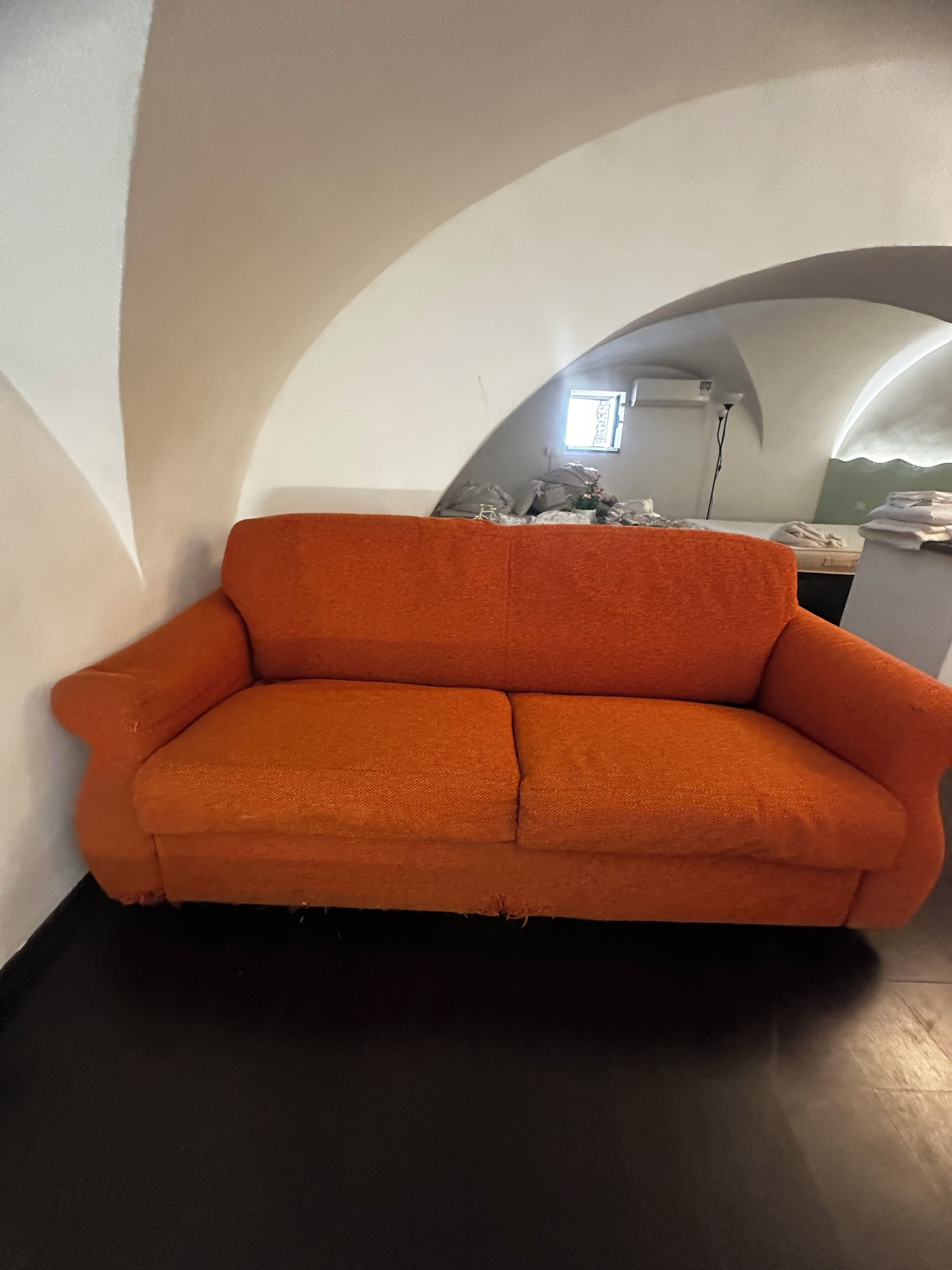 Ein Zimmer mit einer Couch, einem kleinen Tisch und einem Fenster.