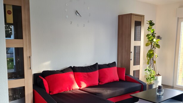 A modern living room with a sectional sofa, a coffee table, and a potted plant. - Trade fair/holiday accommodation (Willich)