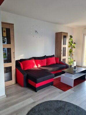 A modern living room with a sectional sofa, a coffee table, and a potted plant. - Trade fair/holiday accommodation (Willich)