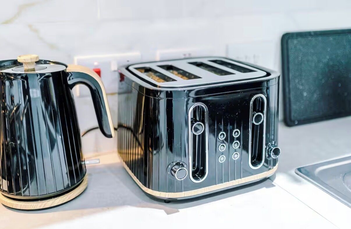 Une cuisine avec un grille-pain noir et une bouilloire noire posés sur le plan de travail.