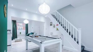 A modern living room with a pool table, a staircase, and a view of the outside. - Modern 2 - Bed House Near Manchester City Centre - Sleeps 6 (Salford)