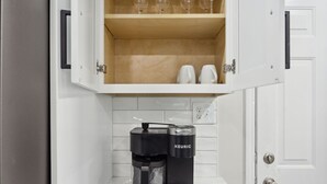 En kaffemaskine på en bordplade med et hvidt skab over.