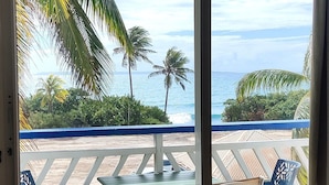 Una stanza con vista sull'oceano, dotata di un balcone con sedie e un tavolo.
