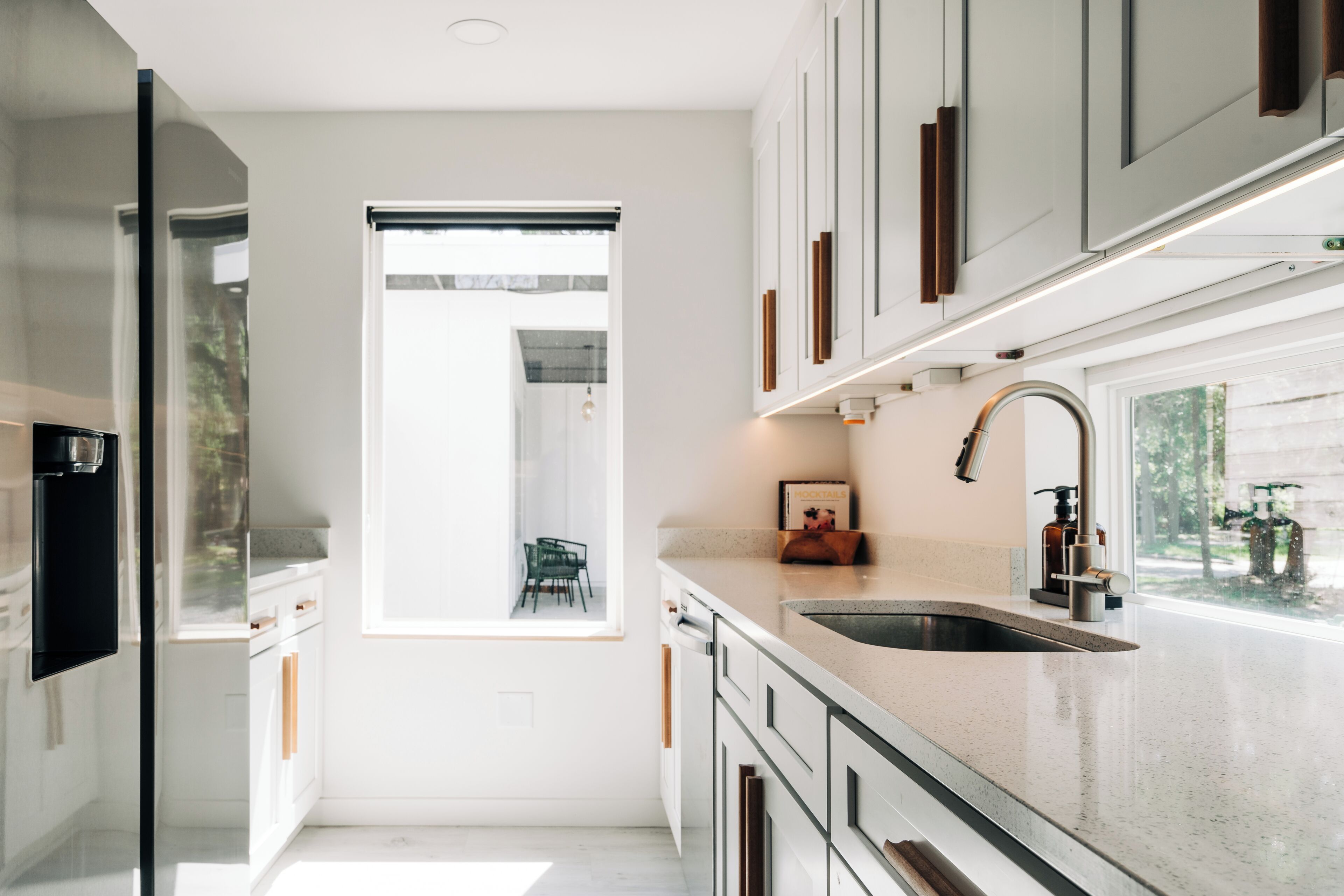 A modern kitchen with white cabinetry, a stainless steel sink, and a window providing natural light.
