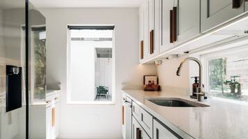 A modern kitchen with white cabinetry, a stainless steel sink, and a window providing natural light.