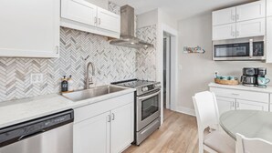 Een moderne keuken met witte kastjes, een roestvrijstalen afzuigkap, een magnetron en een ingebouwde oven.