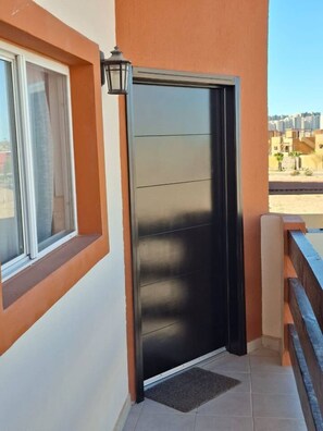 A modern building with a large window and a black door. - 2BR Condo Near Sandy Beach - Pool - Fast WiFi (Puerto Peñasco)