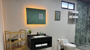 Casa de banho com lavatório preto, sanita branca e uma estante de madeira.