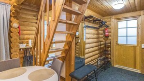 A log cabin interior with a wooden staircase, a dining table, and a fire extinguisher mounted on the wall. - Levin ainola by Interhome (Kittilä)