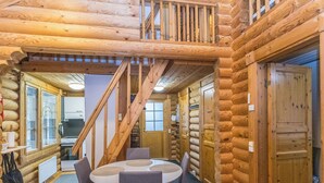 A log cabin interior with a dining area, a staircase, and a kitchen visible through an open door. - Levin ainola by Interhome (Kittilä)