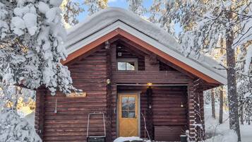 A log cabin with a wooden door, a garage, and a small porch area.