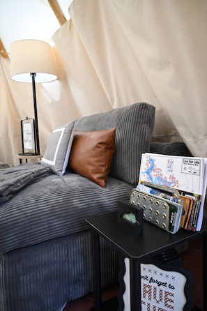 A room with a bed, a lamp, a map, and a small table with a decorative item.