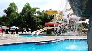 A swimming pool with a water slide and a water fountain. - Comfort and leisure, apartment in the Golden Dolphin Express hotel, fun for the family. (Caldas Novas)