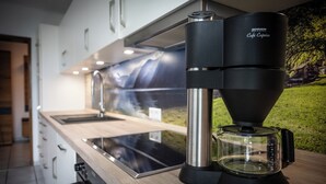 Ett modernt kök med en kaffebryggare, en glaskanna och en vattenkokare i rostfritt stål.