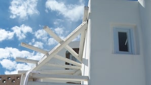 A white building with a sloped roof and a small window. - Christina's Cave House (Santorini)