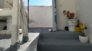 A staircase leading to an open doorway with a clear view of the sky. There are potted plants on the landing. - Christina's Cave House (Santorini)