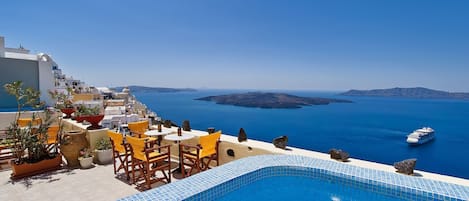 A pool area with a view of the sea and a cruise ship in the distance.