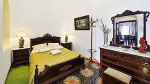 A traditional bedroom with a bed, bedside tables, a dresser, a mirror, and a picture on the wall. - Iriana Apartments (Santorini)