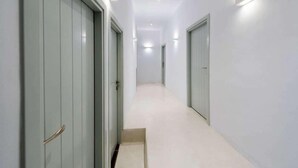 A hallway with white walls and doors, featuring recessed lighting and a carpeted floor. - Iriana Apartments (Santorini)