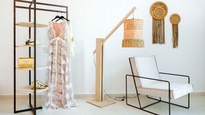 A modern room with a white chair, a dress on a shelf, and wall decor. - Iriana Apartments (Santorini)