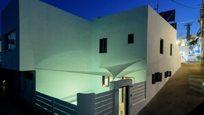 A modern building with a light facade, a visible entrance, and a staircase leading to the entrance. - Sea Dream (Santorini)