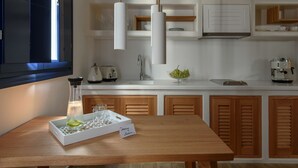 A modern kitchen with wooden cabinets, a white countertop, a coffee machine, and a glass of water on a tray. - Sea Dream (Santorini)