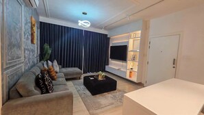 Un salon moderne avec un canapé d’angle, une table basse et un téléviseur à écran plat.