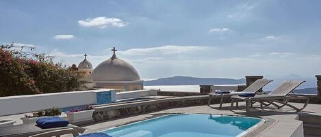 A rooftop pool area with lounge chairs and a view of a dome structure.
