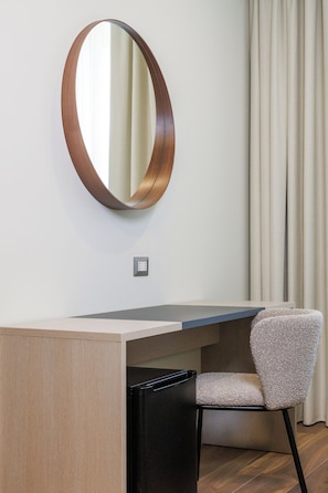A corner desk with a chair, a round mirror, and a light switch on the wall. - Primo Piano Rooms (Aversa)