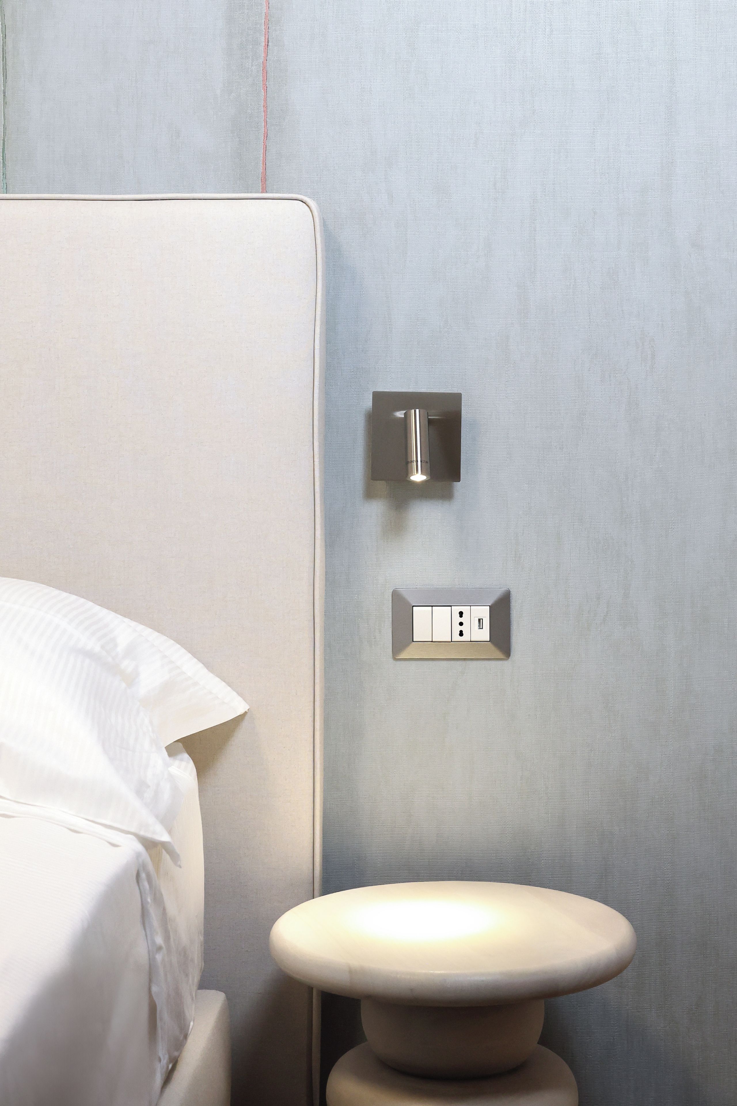 Een badkamer met een wit toilet, een lichtschakelaar op de muur en een stopcontact.