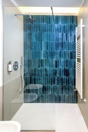A modern bathroom with a glass shower enclosure, a white sink, and a tiled wall. - Primo Piano Rooms (Aversa)