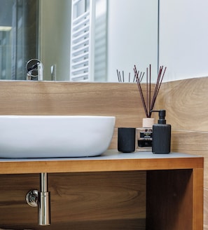 A modern bathroom vanity with a white vessel sink, black soap dispenser, and reed diffuser. - Primo Piano Rooms (Aversa)