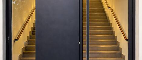 A modern entrance with a dark door and a staircase leading to an upper level.