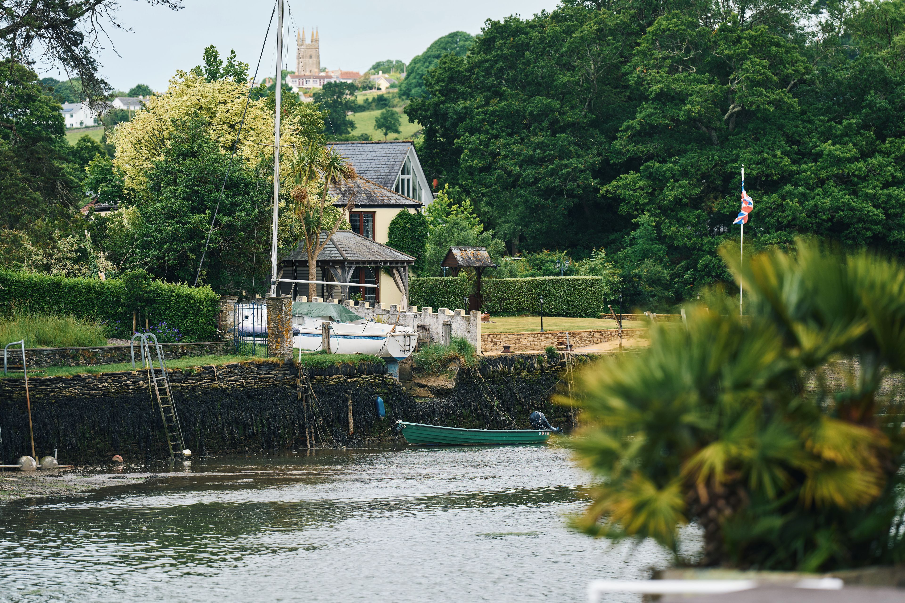 A riverside property with a house, a dock, and boats.