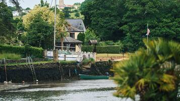 A riverside property with a house, a dock, and boats.