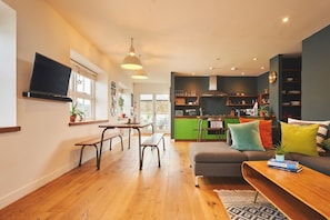 A modern living room with a sofa, a coffee table, and a TV mounted on the wall.