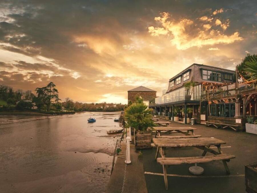 A riverside restaurant with outdoor seating and a view of the river.