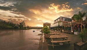 A riverside restaurant with outdoor seating and a view of the river.