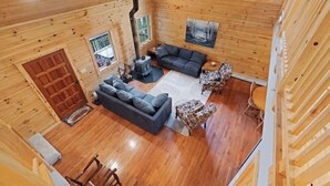 A log cabin interior with a fireplace, a sofa, a patterned armchair, and a dining table. - Enjoyable 4-bedroom cabin with AC in Niagara, on a private 56 acre lake (Niagara)