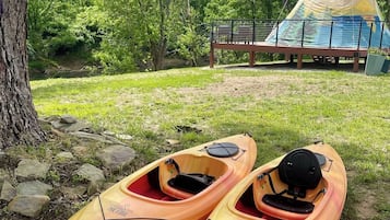 Deux kayaks, un banc et une tente dans un parc.